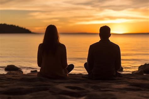 Premium Photo A Couple Sits On The Beach Watching The Sunset