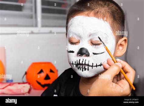 Asian mother and kid son getting makeup halloween face painting look like ghost, Portrait of ...