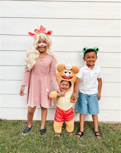 three children standing next to each other in front of a white house ...