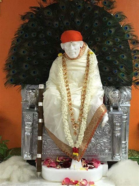 A Statue Of A Man Sitting On Top Of A Silver Chair Next To A Peacock