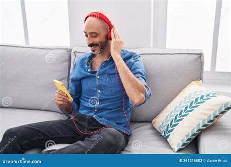 Young Hispanic Man Listening To Music Sitting On Sofa At Home Stock