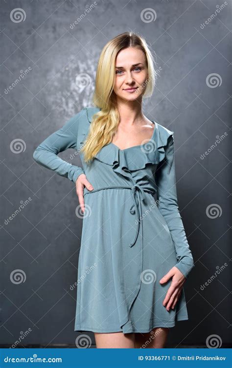 Skinny Blonde Girl In Gray Dress On The Background Of Gray Wall Stock