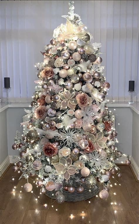 A White Christmas Tree With Pink And Silver Ornaments On Its Top In A