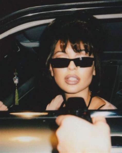 A Woman In Sunglasses Is Sitting In The Back Seat Of A Car And Pointing