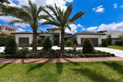 A House With Palm Trees In Front Of It And Landscaping Around The