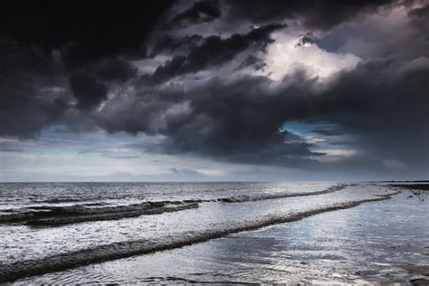 Dark storm clouds over the ocean with waves rolling into the shore;Druridge bay northumberland ...