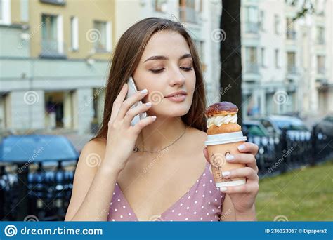 Attractive Girl With Long Hair Is Talking On The Phone And Holding A