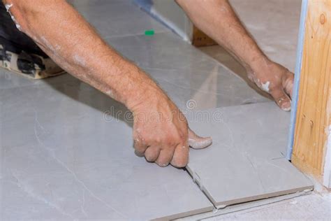 With The Help Of A Home Construction Worker Placing Ceramic Tile On An