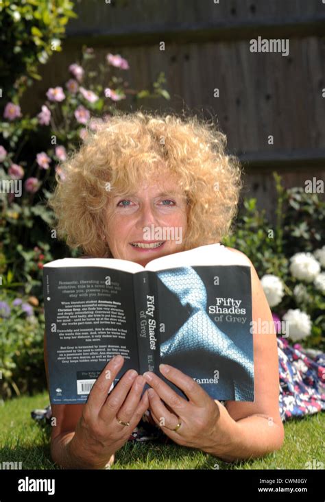 Mature Woman In 50s Reading Sexy Erotic Novel Fifty Shades Of Grey By E L James While Sitting In