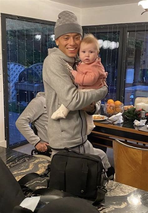 A Man Holding A Baby In His Arms While Standing Next To A Table With