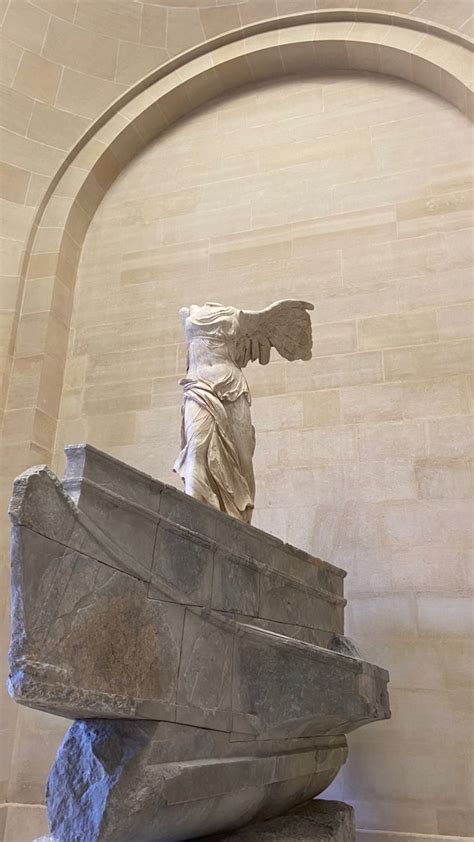 An Angel Statue On Top Of A Stone Block In The Middle Of A Room With Arches