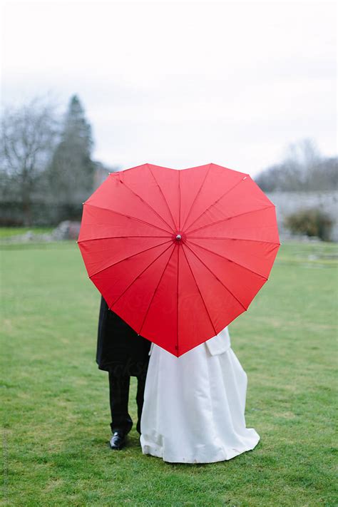 "Wedding Couple Behind Red Heart Umbrella" by Stocksy Contributor "Leah ...