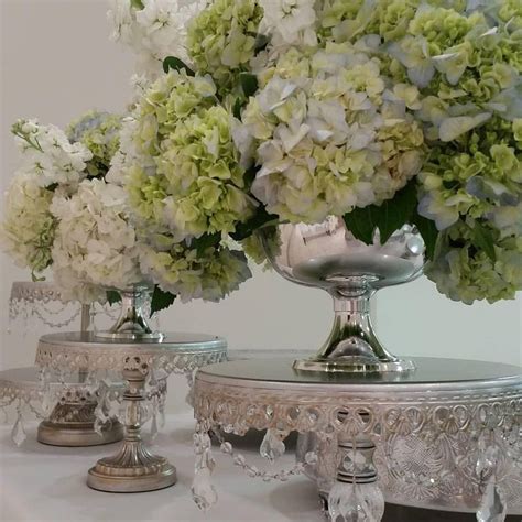 Three Silver Vases Filled With White And Green Flowers