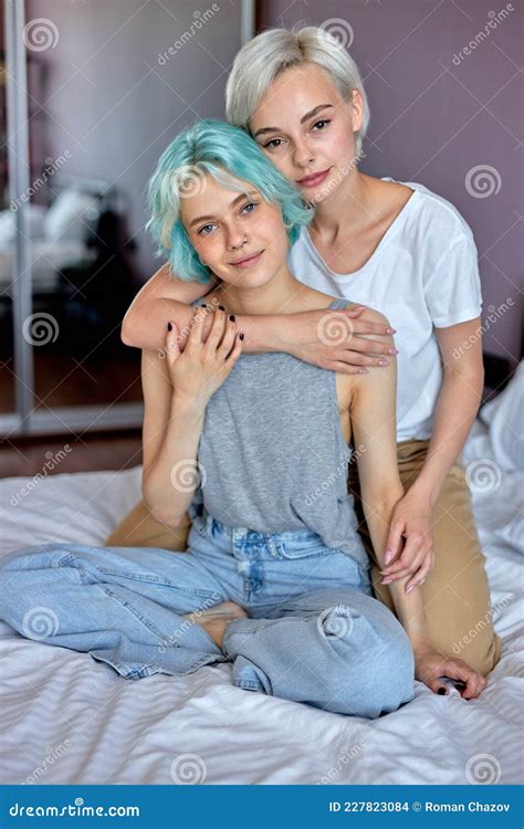 Relaxed Lesbian Couple Embracing On Bed And Looking At Camera Homosexual Couple Stock Photo