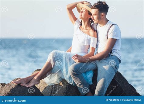 Happy Young Romantic Couple Relaxing On The Beach And Watching The