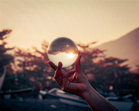 Premium Photo Cropped Hand Of Person Holding Crystal Ball During Sunset