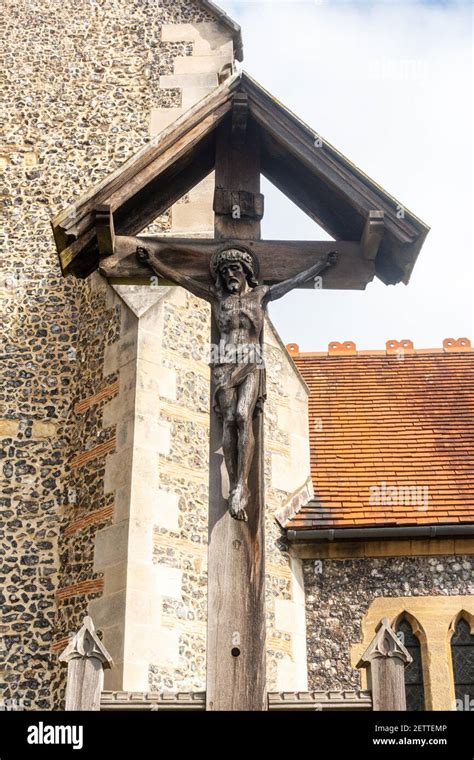 A Carving Of Jesus Christ Being Crucified On A Wooden Cross Stands