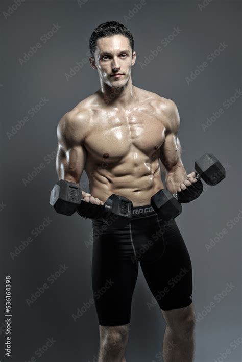 lean muscular man lifting dumbbells stock photo adobe stock