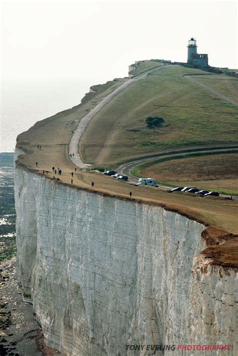 A Group Of People Walking Along The Edge Of A Large Cliff Next To An Ocean