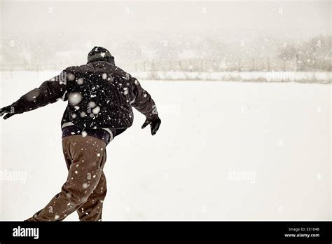 young adult in snow storm throwing a snowball Stock Photo - Alamy