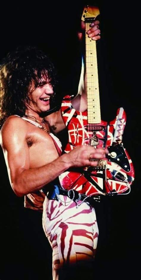 A Man With Long Hair And No Shirt Holding A Guitar In His Right Hand While Wearing Zebra Print