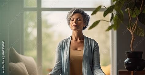 Middle Aged Woman Meditating At Home With Eyes Closed Relaxing Body