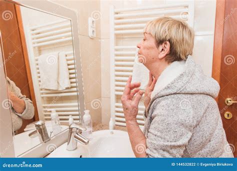 Senior Woman Touching Her Soft Face Skin And Does Massage Looking In