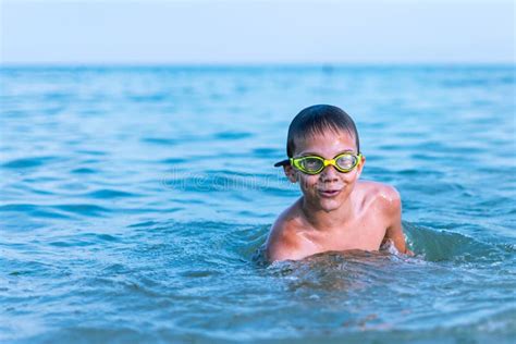 A 10-year-old Boy Swims in the Sea at Dawn with Glasses for Swimming Stock Photo - Image of ...