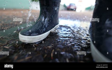 Kid Jumps Into Puddle Of Water Wearing Boots Stock Photo Alamy