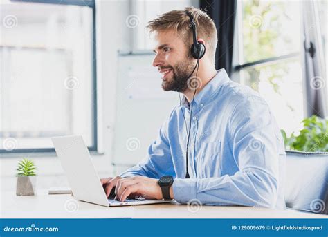side view  smiling young call center operator  headset  laptop