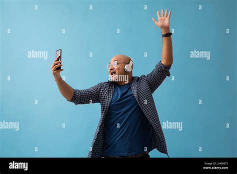 Portrait Of A Bald Man Listening To Music On Headphones And Dancing