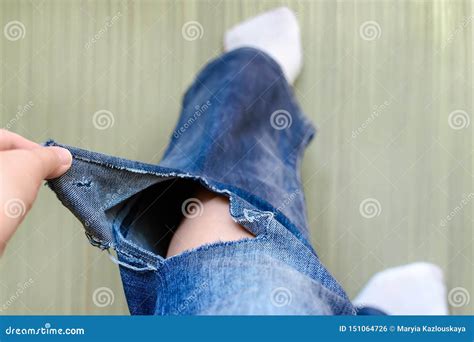 Woman Hand Shows A Hole On A Jeans Woman Dressed In A Blue Jeans With