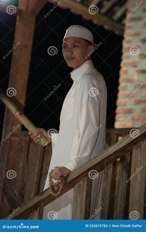 A Muslim Man Standing On The Stairs In Front Of The Traditional House