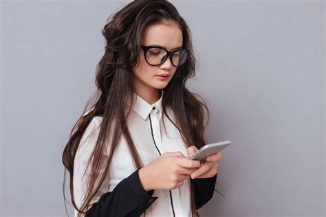 Young Serious Asian Woman In Glasses Writing Message On Phone Side View Isolated Gray