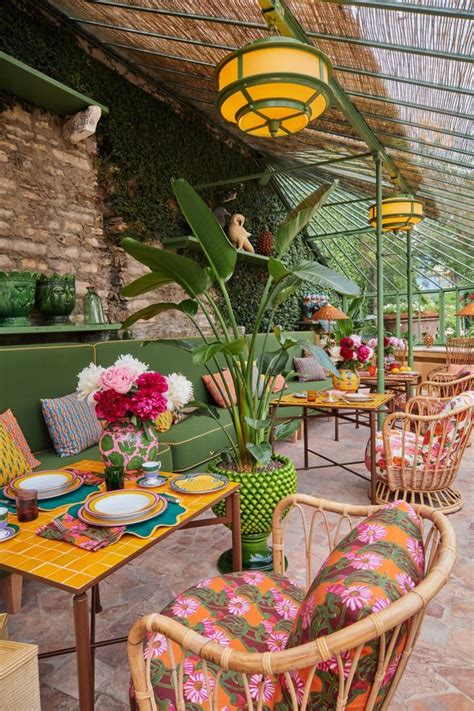 An Outdoor Dining Area With Wicker Chairs And Colorful Tablecloths On