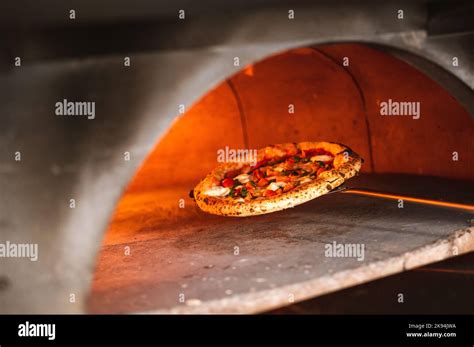 A Closeup Shot Of Pulling Baked Neapolitan Pizza Out From An Oven With