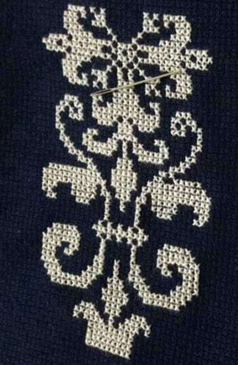 A Close Up Of A Cross Stitch Design On A Black Sweater With White