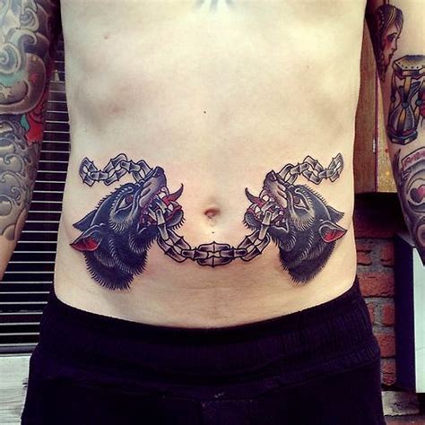 A Man With Tattoos On His Stomach Has Two Wolfs Chained To Chains