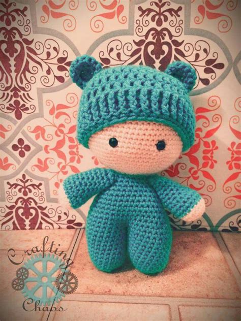 A Small Crocheted Teddy Bear Wearing A Blue Knitted Hat Sitting On Top