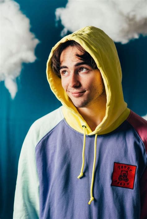 A Young Man Wearing A Yellow Hoodie And Blue Shirt With Clouds In The