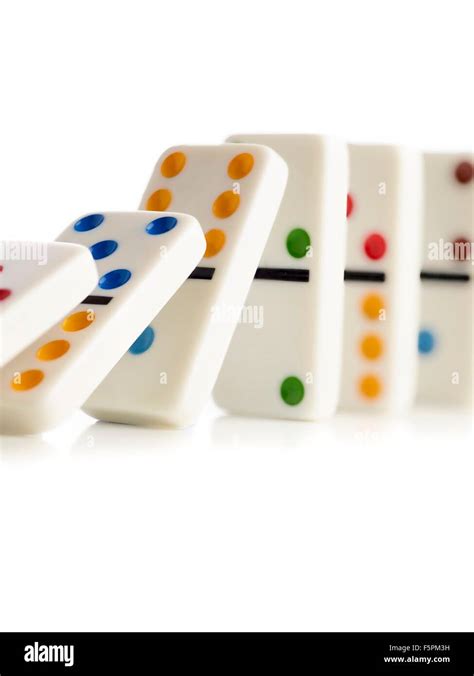 Colourful Dominoes Falling Down Against A White Background Stock Photo