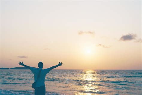 Un Hombre Levantando Las Manos Hacia El Cielo En La Playa Durante Las