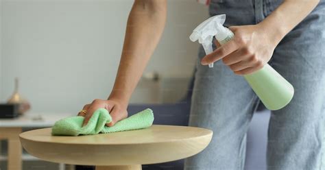 A woman is cleaning a table with a green cloth photo – Cleaning Image ...