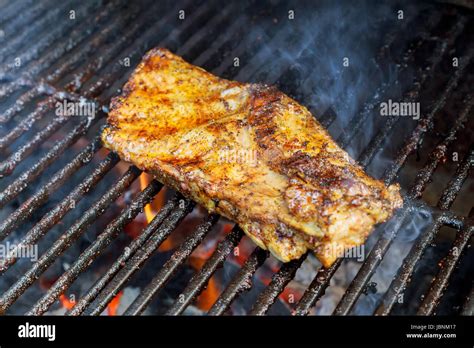 Bbq Pork Ribs Cooking On Flaming Grill Shot With Selective Focus Stock