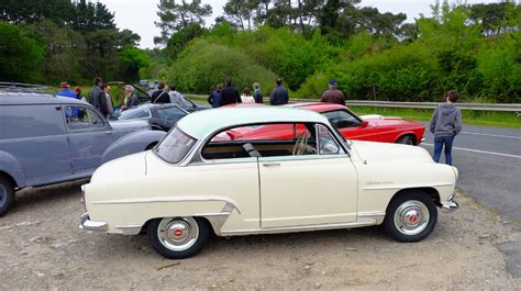 An Old Car Is Parked Next To Other Cars On The Side Of The Road With