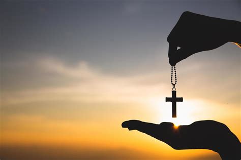 Silhouette Of Hand Holding Necklace Crucifix Background Sunrise