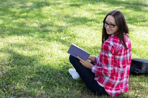 Premium Photo Woman Sitting On The Grass And Reading Book