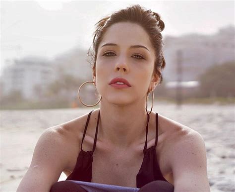 A Woman Sitting On The Beach With Her Arms Crossed Wearing Large Hoop