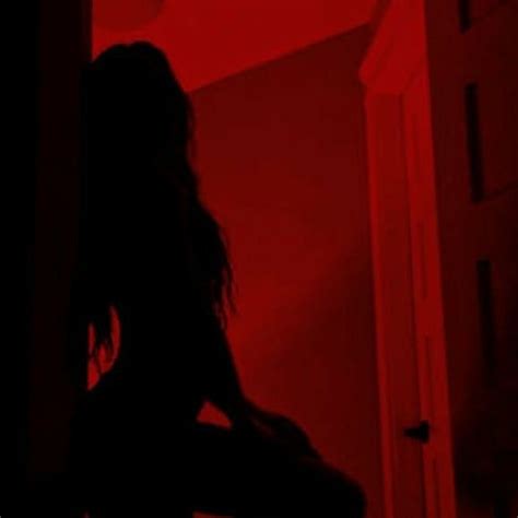 The Silhouette Of A Woman Sitting In Front Of A Red Light