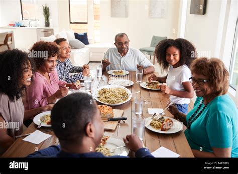 Three generation black family sitting at the table talking and eating ...